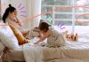 A working mom and her daughter in the bedroom, Mom is working while daughter is playing with her toys.