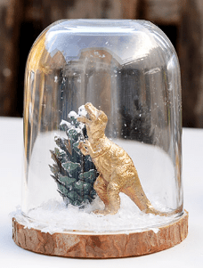 An image of a Christmas craft made with cloche and dinosaur ornaments 
