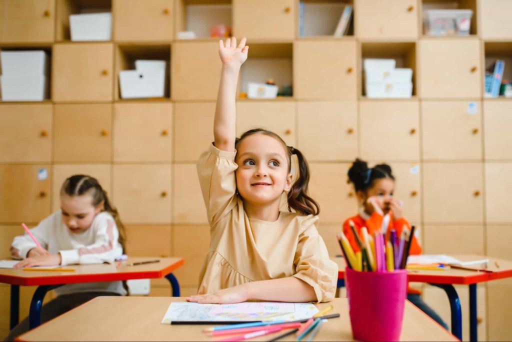 An image of a kid raising her hand in class 