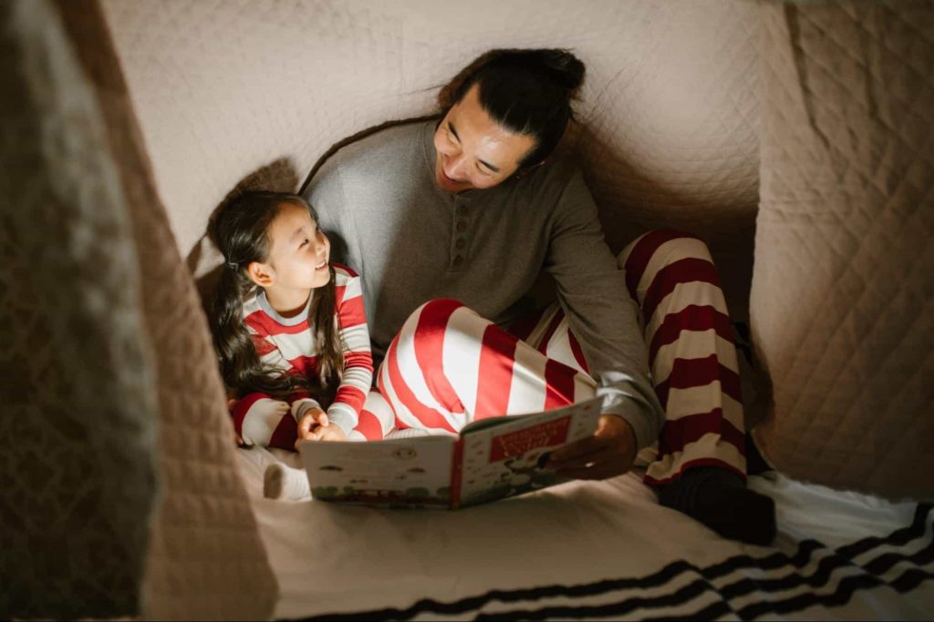 An image of a girl reading a book with her father - how to teach reading
