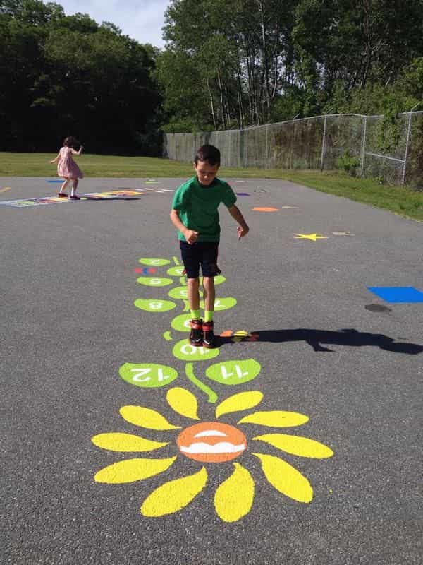 An image of a kid playing on a hopscotch pattern