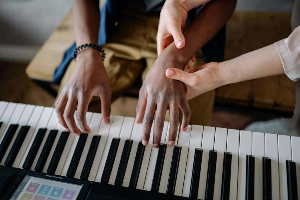 An image of a teacher teaching piano to a kid slowly