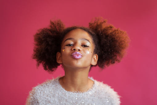 Lovely teenage girl with bright festive makeup against pink background An image of a teenager with makeup on fun indoor play for kids
