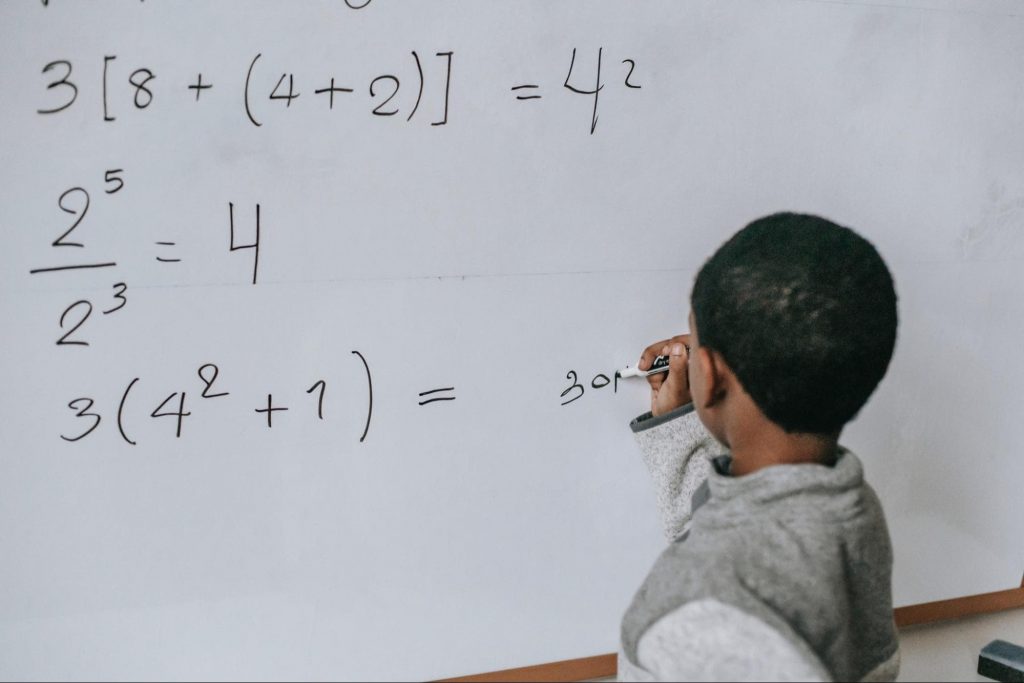 A child solving a math problem on a whiteboard 