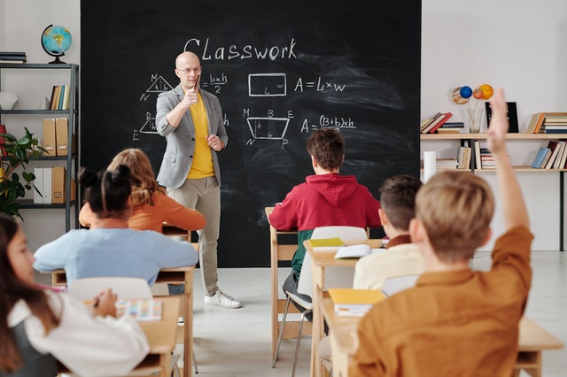 Teacher asking questing from students and student raising hand