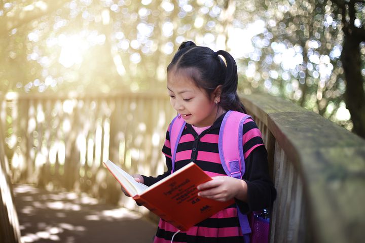 Child reading outdoor guide book in outdoor classroom