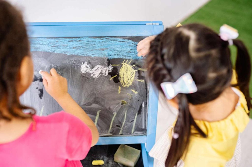 Children making art with colored chalks on board universal design for learning 5