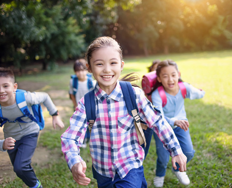 Group of school kids running on the grass outdoor classroom