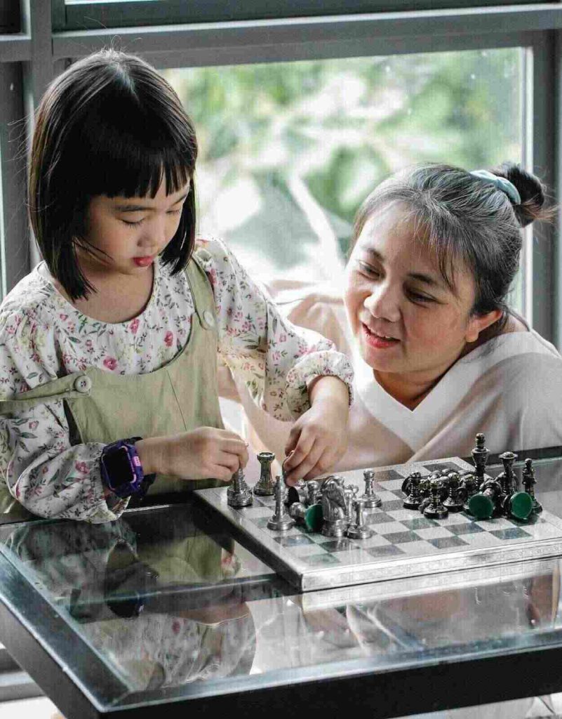 Elder lady telling young girl about chess brain teasers for kids