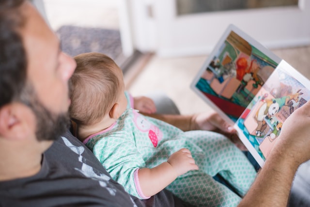 Father reading comic book to child 