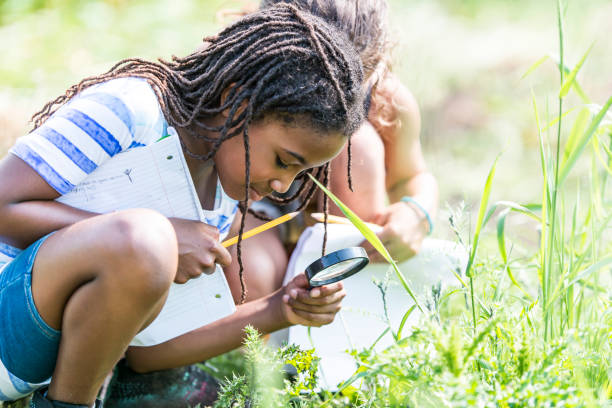 Girl looking at grass with magnifying glass outdoor classroom