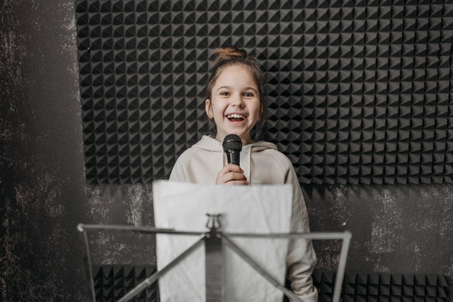 Kid holding a microphone inside a studio phonological disorder