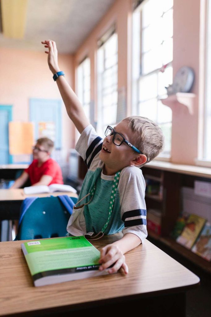 Little child smiling in class raising hand universal design for learning 3