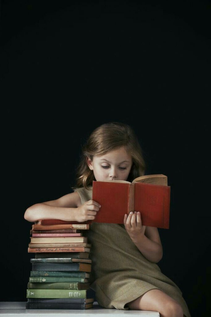Little girl using reading strategy for novel
