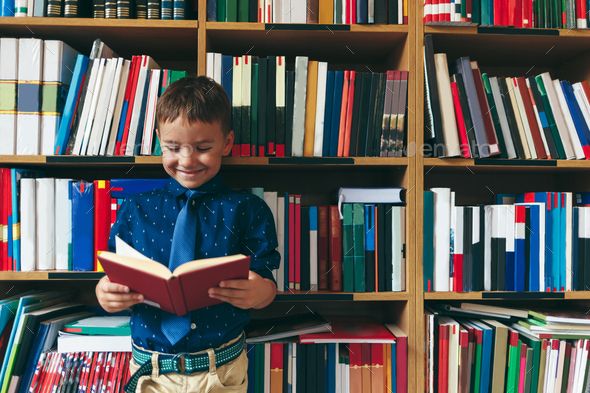 Little child smiling reading a book in library