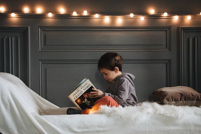 Small boy in jacket reading a book how to read a book Small boy in jacket reading a book how to read a book