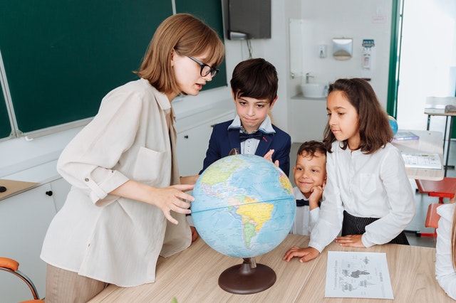 Teacher discussing with students about the globe Types of Assessments