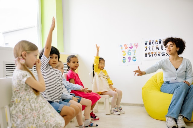 Teacher explaining to little kids rasing hands Types of Assessments