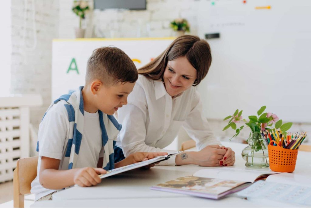 Image of a teacher smiling while teaching a student 