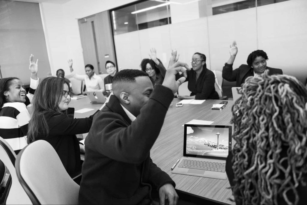 classroom2 Image of students raising hands in hybrid class