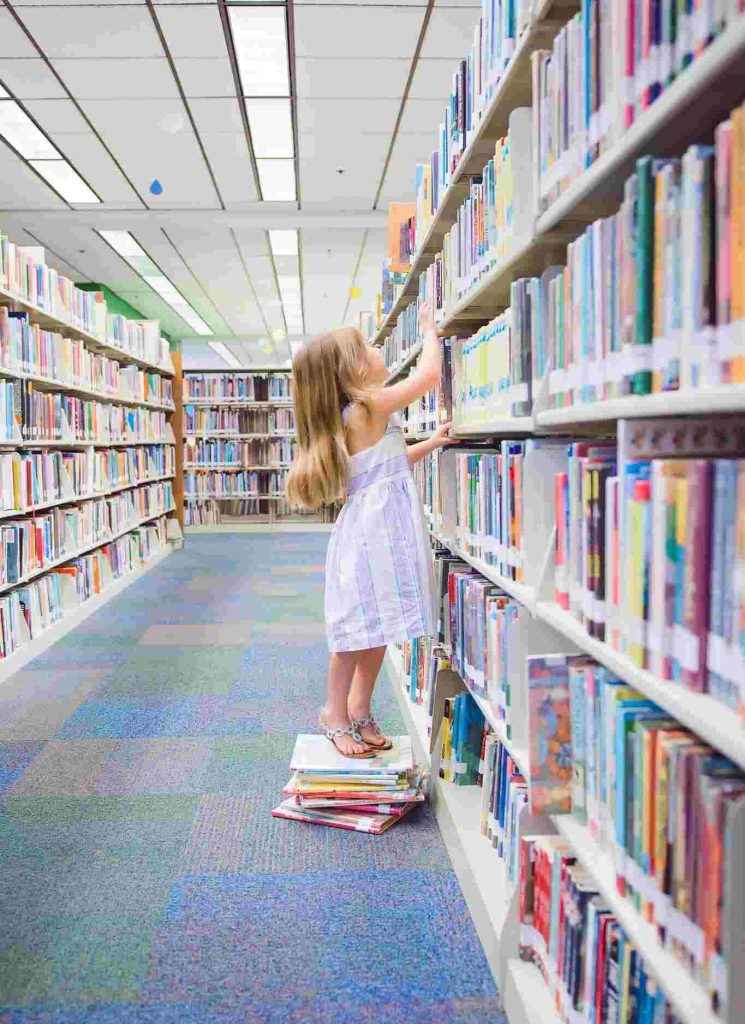 Girl in library looking for book reading strategies