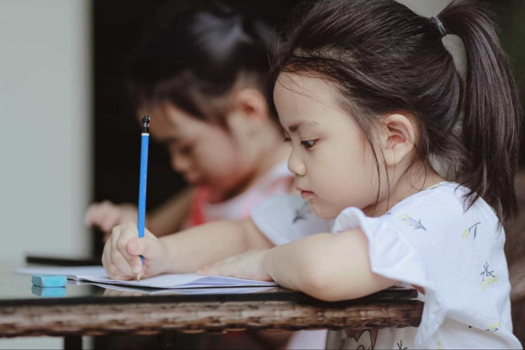 Image of a little girl holding a pencil and writing something