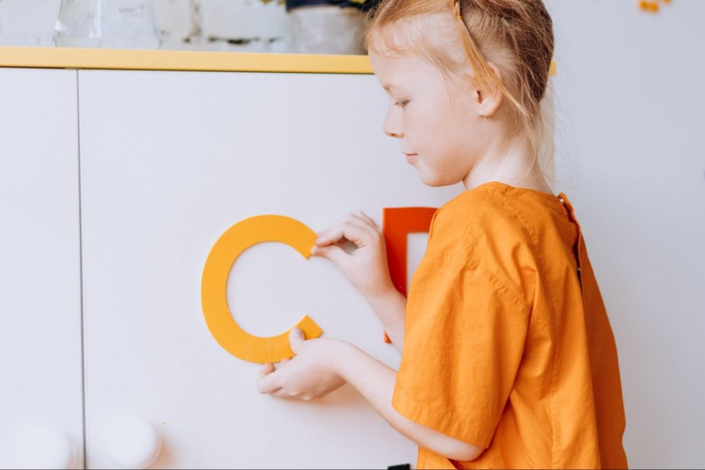 Image of a kid pasting letters on a white board 
