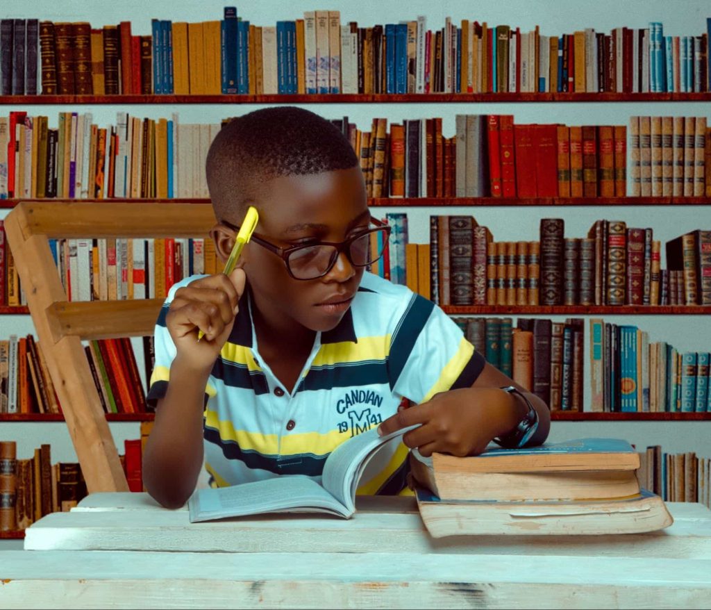studentthinking | SplashLearn Image of a student sitting in a library and thinking something