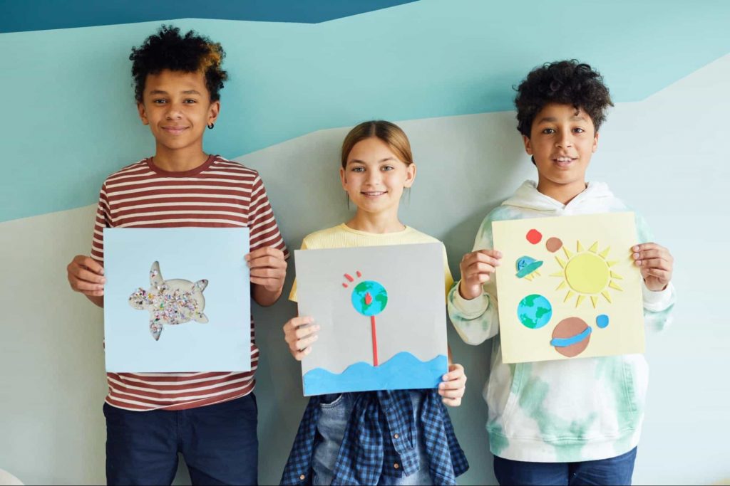 Image of students holding their paintings and drawings 