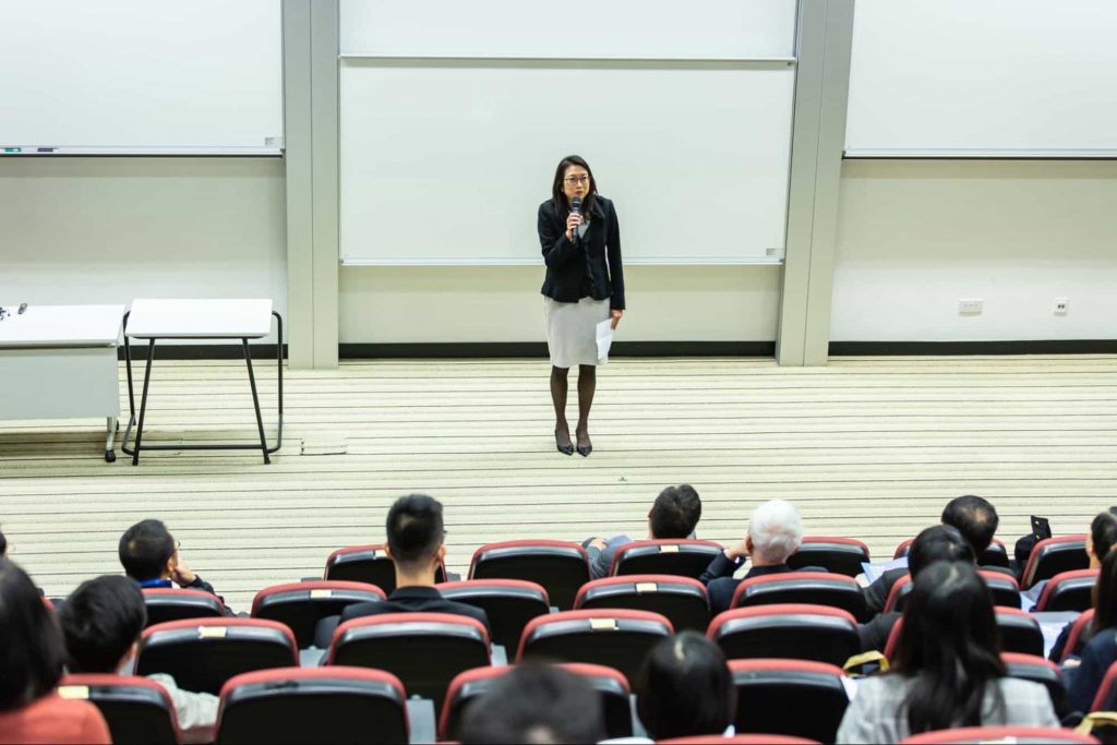 Image of a teacher standing in a clasroom 
