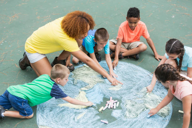 teaher showing children chalk drawings in outdoor classroom