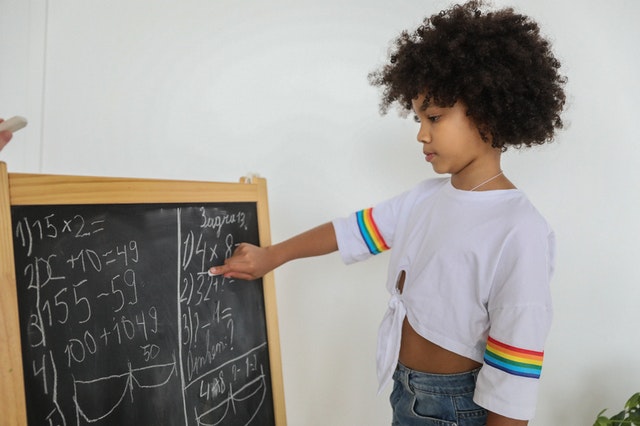 African American student pointing on math symbols on board
