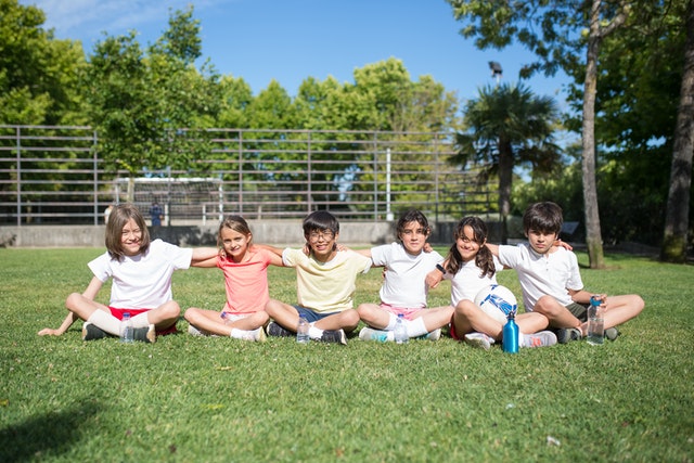 Children sitting in grass team building activities for kids