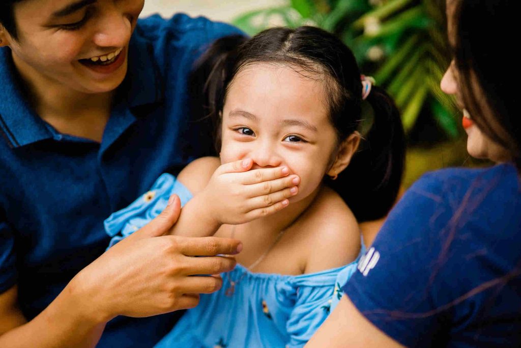 Young girl laughing with parents at fun facts for kids