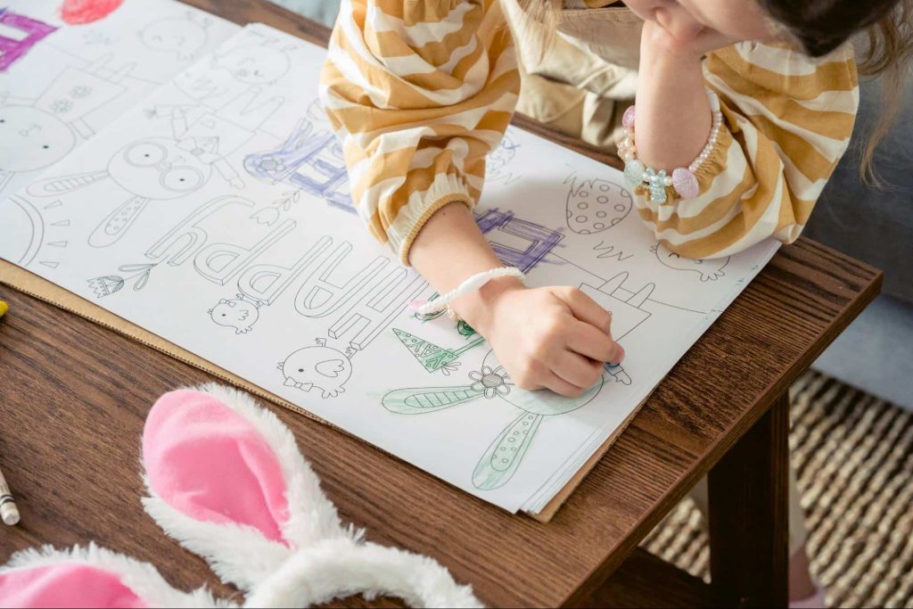 Image of a kid drawing something on a white paper 