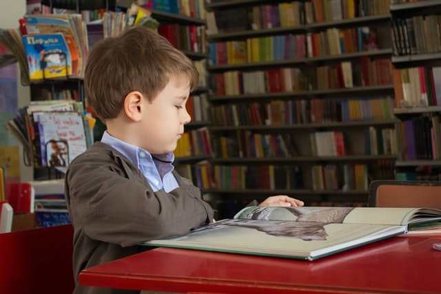 Image of a kid reading a book in the library 