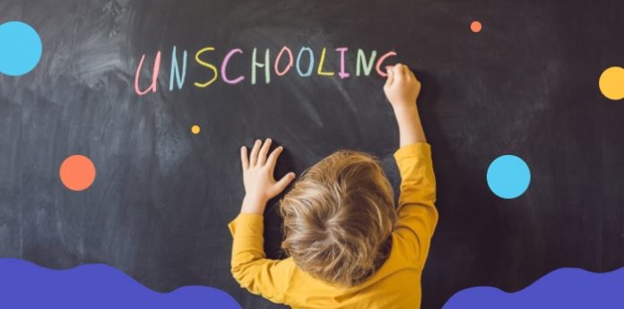 Kid writing unschooling on blackboard