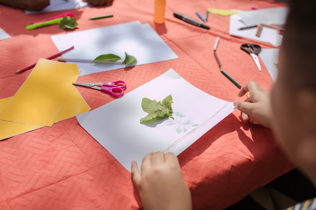 Child making art with leaf summer camp kids