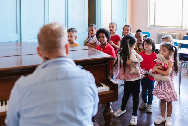 Children standing inside room with music teacher self care for teachers