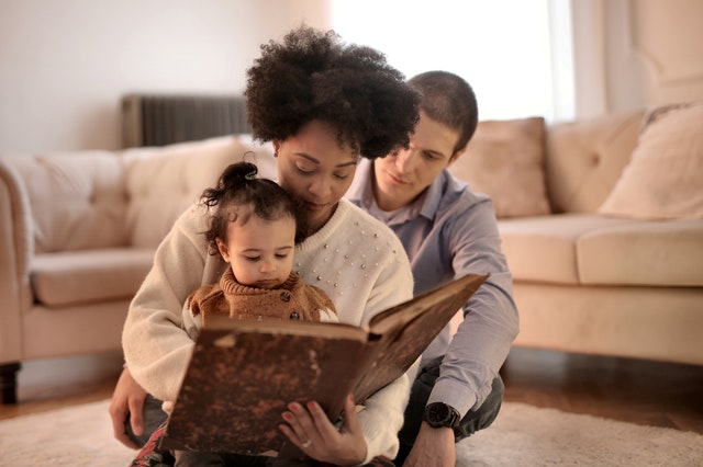 Image of parents reading book with child as storytelling for kids has many benefits 