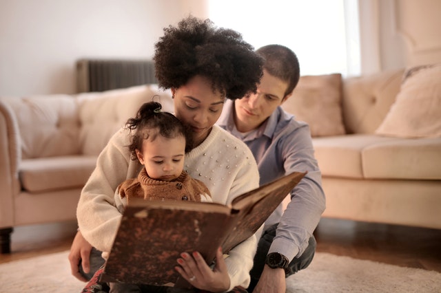 Image of parents reading book with child as storytelling for kids has many benefits