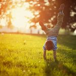 Little boy doing hand stands on grass Spring activities for preschoolers