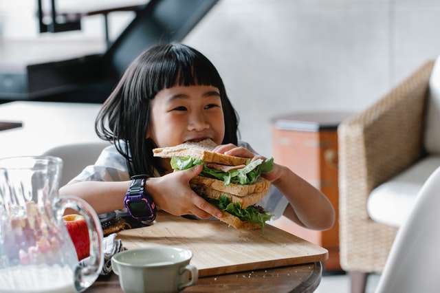 Little girl eating huge delicious sandwich Healthy Snacks for Kids Little girl eating huge delicious sandwich Healthy Snacks for Kids