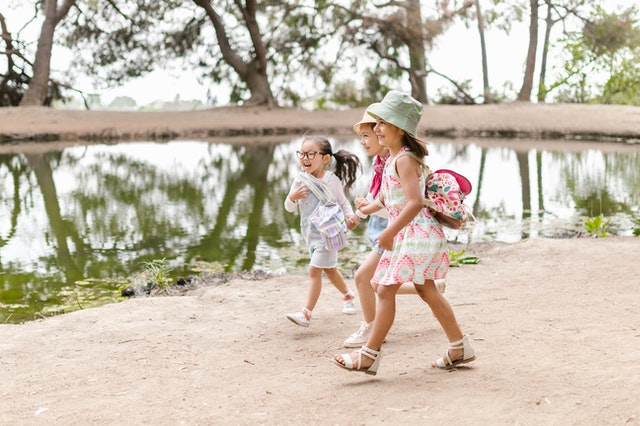 Little girls walking near body of water summer camp kids Little girls walking near body of water summer camp kids
