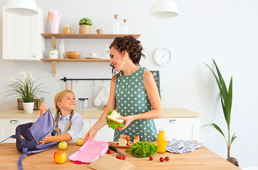 Mother and daughter packing healthy lunch in bag lunch ideas for kids