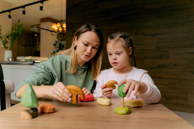 Mother and girl playing toys together developmental disabilities Mother and girl playing toys together developmental disabilities