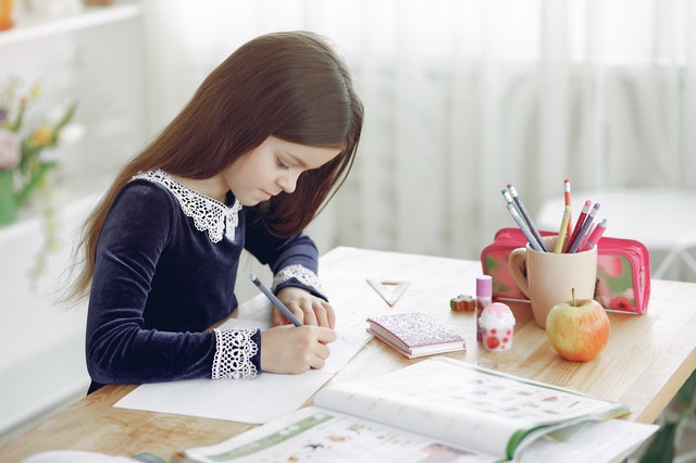 Schoolgirl writing in notebook sitting at table journal prompts for kids