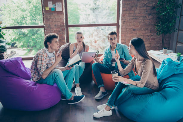 Students sitting on bean bags in break room discussing debate topics for kids