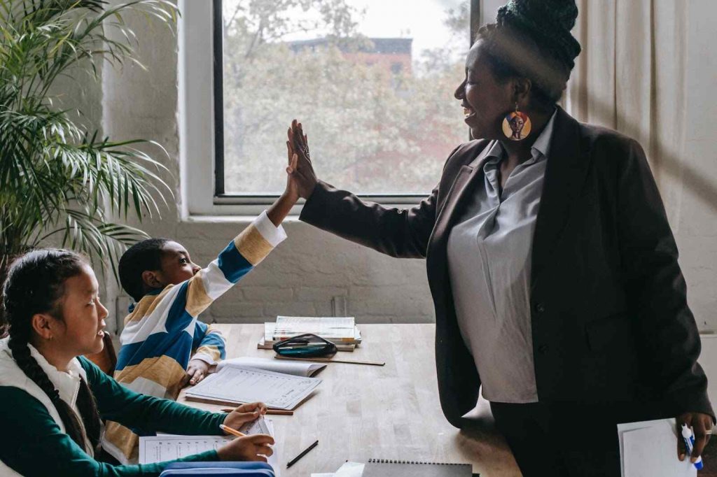 Teacher high fiving students restorative practices in the classroom