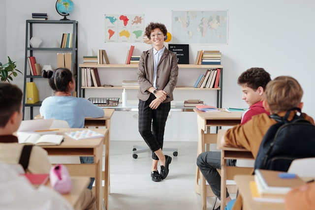 Teacher standing in the classroom What is taught to kids in 5th grade Teacher standing in the classroom What is taught to kids in 5th grade